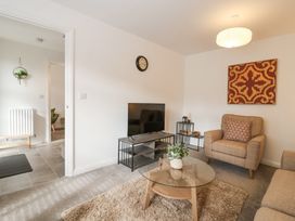 A living room with a glass coffee table holding a plant and a TV on a stand at Peninsula Cottages - The Tors in Tavistock