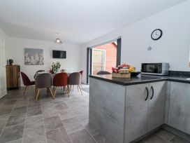 A dining area with a table and chairs next to an open doorway and a kitchen counter with snacks and microwave at Peninsula Cottages - The Tors in Tavistock
