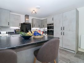 A modern kitchen with an island countertop two chairs and built in cabinets at Peninsula Cottages - The Tors in Tavistock