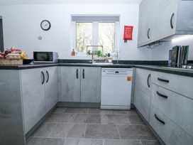 A kitchen with gray cabinets a microwave dishwasher and a window at Peninsula Cottages - The Tors in Tavistock