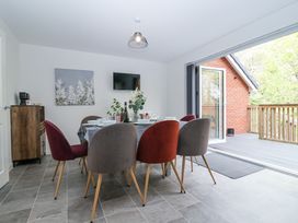 A dining room with a table set for a meal and chairs around it next to an open door leading to a balcony at Peninsula Cottages - The Tors in Tavistock