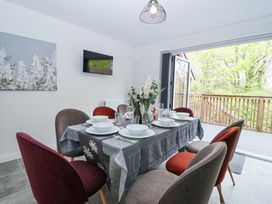 A dining room with a table set for six near open doors leading to a balcony at Peninsula Cottages - The Tors in Tavistock
