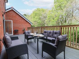 An outdoor patio with wicker furniture and a table set with plates and glasses at Peninsula Cottages - The Tors in Tavistock