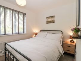 A bedroom with a double bed a window with blinds two bedside tables with lamps and a painting on the wall at Peninsula Cottages - The Tors in Tavistock