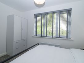 A bedroom with a white wardrobe a window with blinds and a bed at Peninsula Cottages - The Tors in Tavistock