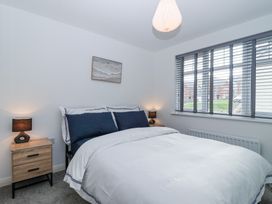 A bedroom with a bed with navy and white bedding bedside tables with lamps and a window with blinds at Peninsula Cottages - The Tors in Tavistock