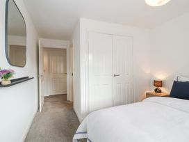A bedroom with a bed a bedside table with a lamp a wall mirror and a closet at Peninsula Cottages - The Tors in Tavistock