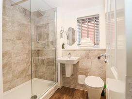 A bathroom with a shower, sink, toilet, and window with blinds at Peninsula Cottages - The Tors in Tavistock