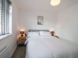 A bedroom with a bed between two nightstands with lamps and a window with blinds at Peninsula Cottages - The Tors in Tavistock