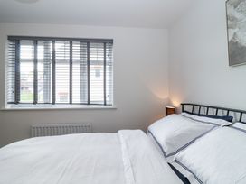 A bedroom with a bed and bedside lamp near a window with blinds at Peninsula Cottages - The Tors in Tavistock