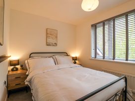 A bedroom with a double bed bedside tables lamps a window with blinds and a painting on the wall at Peninsula Cottages - The Tors in Tavistock