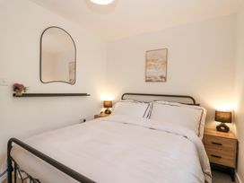 A bedroom with a bed a mirror a shelf with flowers and bedside tables with lamps at Peninsula Cottages - The Tors in Tavistock