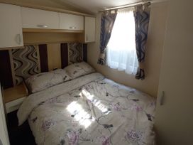 A bedroom with a bed and shelves at Emma No.6 Llandegfan
