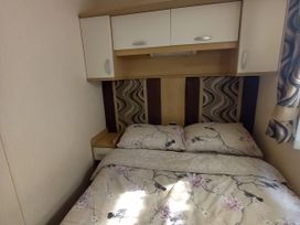 A bedroom with a bed and bedside cabinet at Emma No.6 in Llandegfan