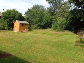A garden with a wooden shed and greenery at Emma No.6 in Llandegfan