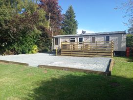 A mobile home with a deck and gravel area at Emma 6 in Llandegfan