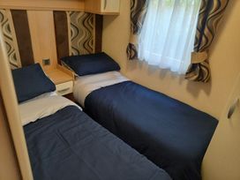 A bedroom with two beds and a window at Emma 6 in Llandegfan