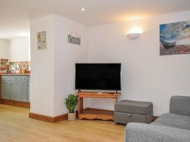 A living room with a television and a sofa at Norvys in Bossiney