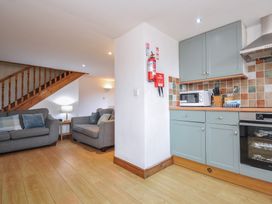 A living room with a sofa and kitchen area at Norvys in Bossiney