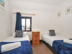 A bedroom with two single beds and a nightstand at Norvys in Bossiney