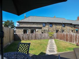A garden with a stone building and pathway at Norvys in Bossiney