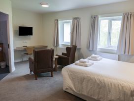 A bedroom with a bed, chairs, desk and television at Bedroom 36 in Penrith