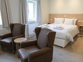 A bedroom with a bed and two armchairs at Bedroom 36 in Penrith