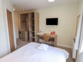 A bedroom with a bed, wardrobe, desk, and TV at Eamont Park First-floor Double Bedroom in Penrith