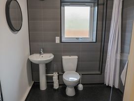A bathroom with a toilet, sink, mirror, and window at Bungalow 19 Eamont Park Penrith