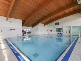 An indoor swimming pool with poolside and chair at Bungalow 19 Eamont Park Penrith