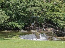 A waterfall flowing into a river surrounded by trees at Bungalow 15 Eamont Park Penrith