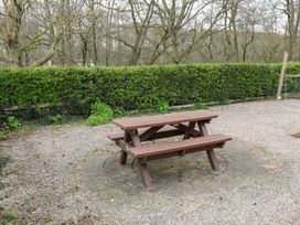 A picnic table in a gravel area surrounded by green hedge and trees at Bungalow 14 Eamont Park Penrith