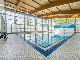 An indoor pool with deck chairs and large windows at Jubilee Two Bedroom Accessible Bungalow Pet Friendly Penrith