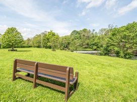 A bench overlooking a river in a green outdoor area at Jubilee Two Bedroom Accessible Bungalow Pet Friendly Penrith