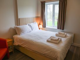 A bedroom with a bed, nightstand, and window at Bedroom 7 in Penrith