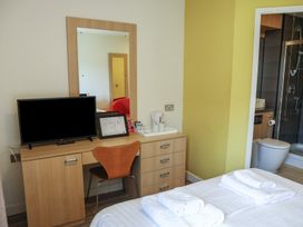 A bedroom with a desk, television, and bathroom at Bedroom 7 in Penrith
