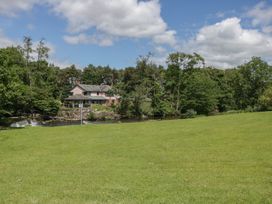 A house by a river surrounded by trees and grass at Bedroom 7 in Penrith