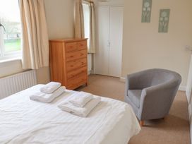 A bedroom with a bed, dresser, and chair at House 8 Eamont Park in Penrith