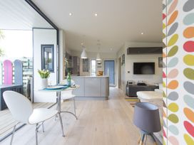 A kitchen and living area with a small round dining table and chairs in a modern open plan space at Two Bare Feet in Rose near Perranporth