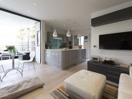 A modern open-plan living room and kitchen with white chairs and a table at Two Bare Feet in Rose near Perranporth