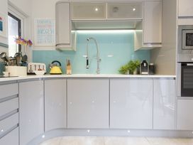 A kitchen with a curved counter white appliances and a blue backsplash at Two Bare Feet in Rose near Perranporth