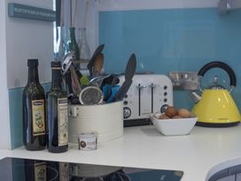 A kitchen countertop with utensils, olive oil and balsamic vinegar bottles, a toaster, a bowl of eggs, and a yellow kettle at Two Bare Feet Rose near Perranporth