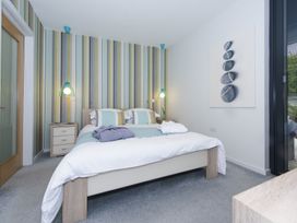 A bedroom with a double bed striped wallpaper bedside tables and lamps at Two Bare Feet Rose near Perranporth
