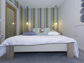 A bedroom with a double bed two bedside tables and wall lamps at Two Bare Feet in Rose near Perranporth
