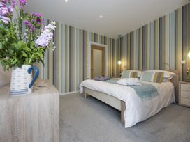 A bedroom with a double bed bedside tables with lamps and flowers on a dresser at Two Bare Feet Rose near Perranporth