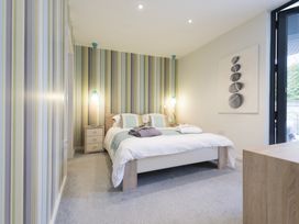 A bedroom with a double bed and striped wallpaper at Two Bare Feet in Rose near Perranporth