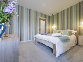 A bedroom with a bed and striped wallpaper at Two Bare Feet in Rose near Perranporth
