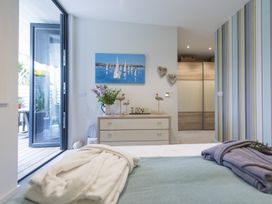 A bedroom with a dresser flowers and bird decorations and an open door to a patio at Two Bare Feet Rose near Perranporth