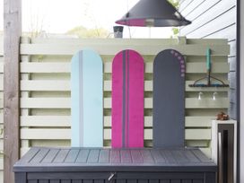 A wooden fence with three colorful wooden panels and a tool hanging holding two wine glasses at Two Bare Feet Rose near Perranporth