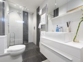A bathroom with a toilet shower area and sink with towels and toiletries at Two Bare Feet in Rose near Perranporth